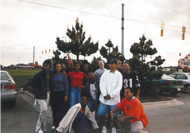 Students posing in a parking lot smiling at camera